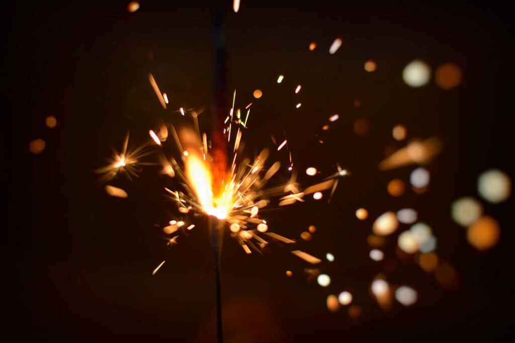 Capture the energy of fireworks with this close-up of a sparking firecracker, bursting with light.